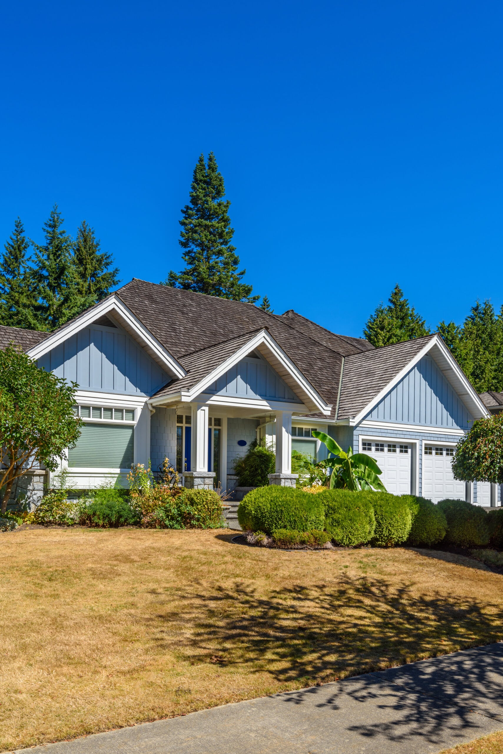 Luxury residential house in Vancouver, Canada, featuring a modern design, landscaped front yard, and clear blue sky, representing high-quality construction services by Clarke Building Company.