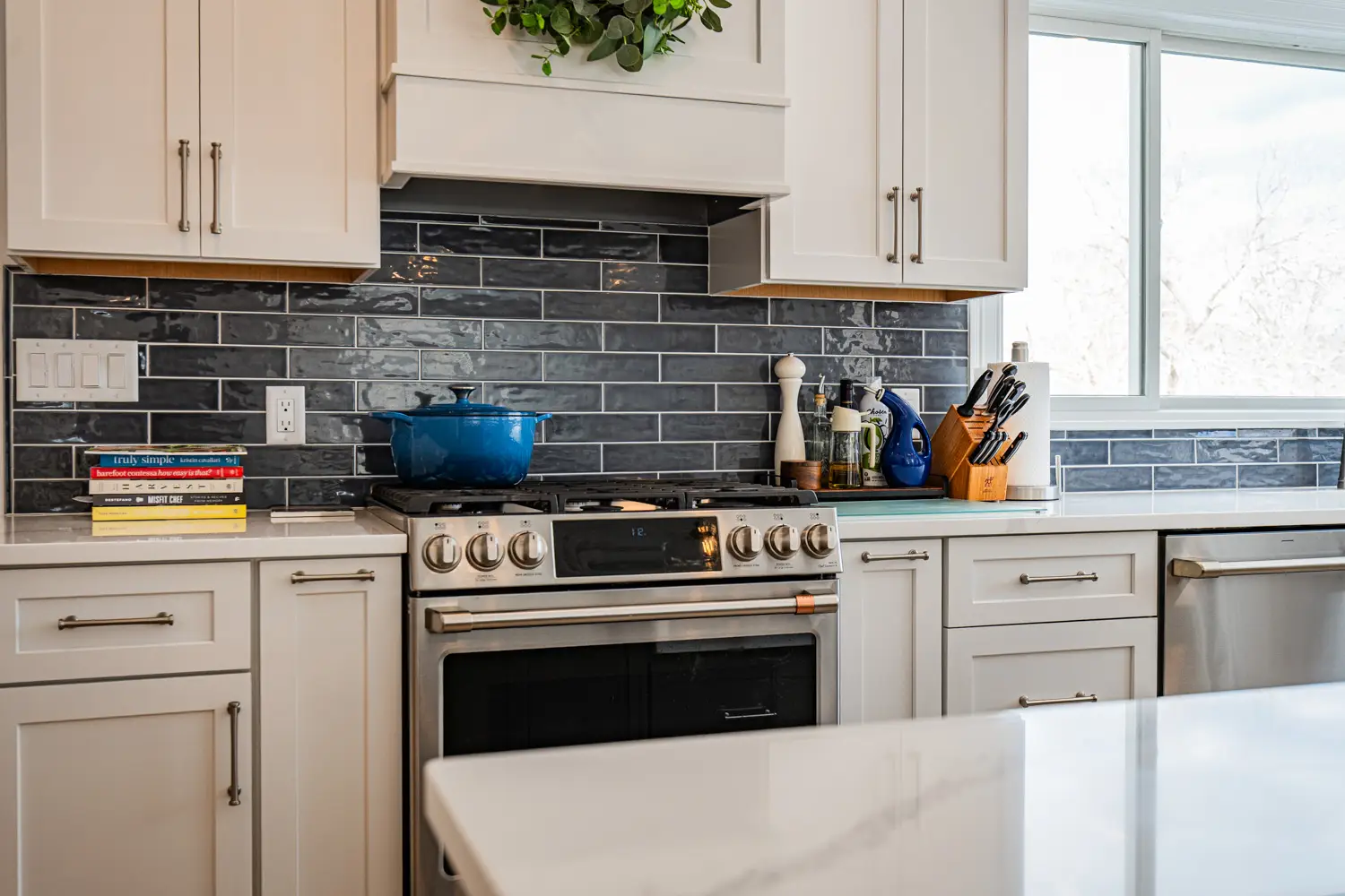 Modern white kitchen cabinetry and dark tile backsplash with stainless steel appliances for North Shore homeowners.